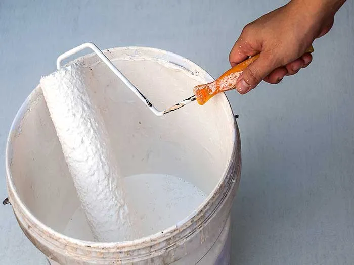 dipping paint roller into paint